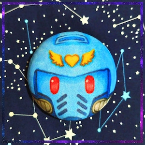 May include: A blue, cartoon-style helmet with red eye details, gold accents, and a gold heart and wing design. Set against a dark blue background with white stars and constellations, framed by a purple border.
