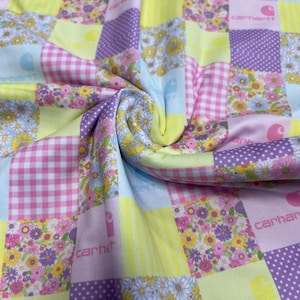 May include: Patchwork fabric with a floral and gingham pattern in pink, yellow, purple, and blue. The fabric features the Carhartt logo repeated throughout.