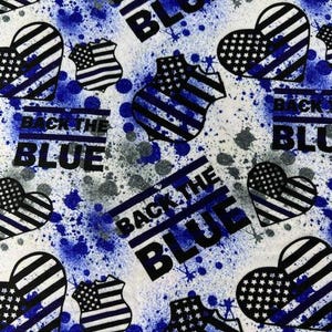 May include: White fabric with a blue and gray splatter design. The fabric features repeating patterns of heart shapes and police badge shapes with the American flag design. The words "BACK THE BLUE" are printed in black.