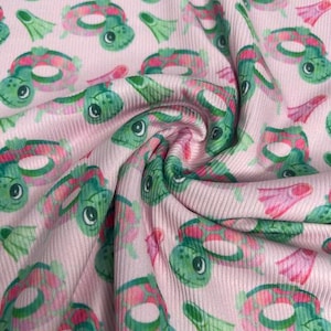 May include: Pink fabric with a repeating pattern of green turtles wearing life preservers and pink flippers.