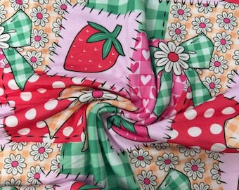 May include: A colorful fabric with a patchwork design featuring strawberries, daisies, polka dots, and gingham bows. The strawberries are red with green stems, and the bows are green and white. The background is a mix of pink, orange, and white.