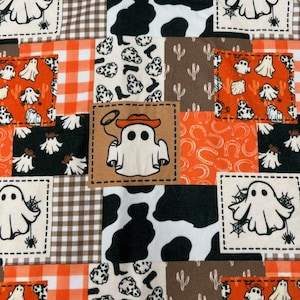 May include: A patchwork fabric design featuring various patterns and images. Squares include a ghost with a spiderweb, a ghost wearing a cowboy hat, cow print, and orange gingham. The color palette includes orange, brown, black, and white.