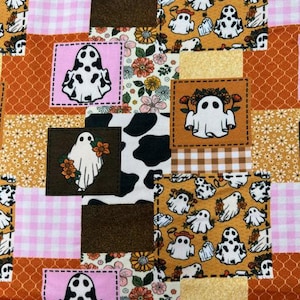 May include: A patchwork design featuring various patterns and colors. The design includes squares with ghost illustrations, floral prints, cow print, and gingham. The color palette consists of orange, brown, pink, and white.