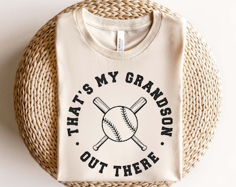 May include: A beige t-shirt with a black graphic that says "That's my grandson out there." with a baseball and crossed bats.