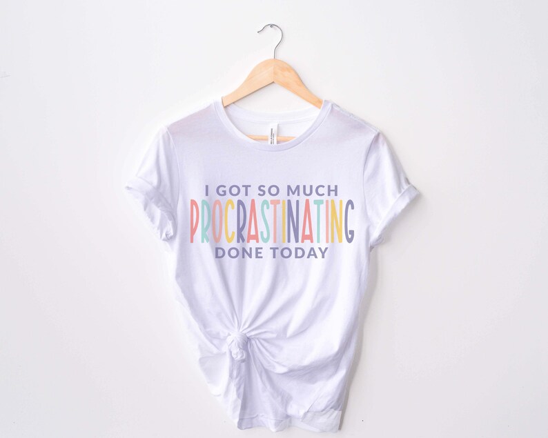 Peut inclure: T-shirt blanc avec un graphique arc-en-ciel qui dit "J'ai tellement procrastin&eacute; aujourd'hui."