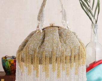 May include: A gold and silver beaded clutch bag with a long fringe. The bag has a gold clasp and a top handle.