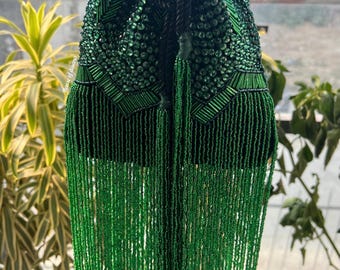 May include: A drawstring pouch bag in deep emerald green, heavily embellished with matching green beads, sequins, and tube beads. The bag features a long, dense fringe of green seed beads at the base and a thick black cord drawstring closure.