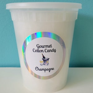 May include: A white plastic container filled with gourmet cotton candy, labeled "Gourmet Cotton Candy Champagne".