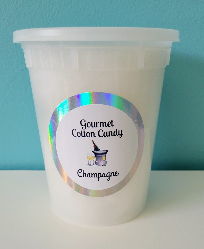 May include: A white plastic container filled with gourmet cotton candy, labeled "Gourmet Cotton Candy Champagne".