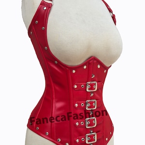 Puede incluir: Corsé de cuero rojo con hebillas y tachuelas plateadas. El corsé tiene un diseño de correa halter y una parte inferior puntiaguda.