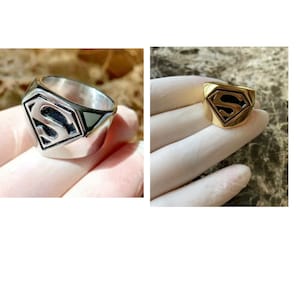 May include: Two Superman rings, one silver and one gold, with the Superman logo on the top.