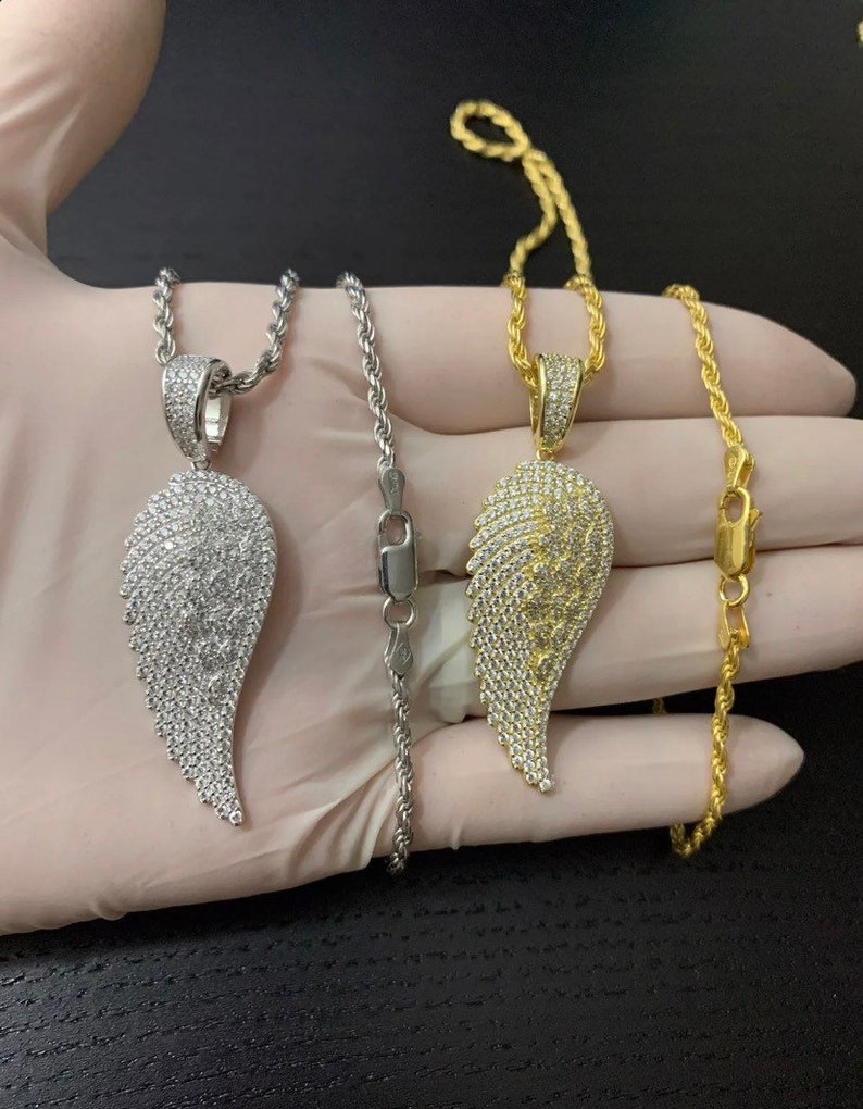 May include: Two silver and gold rope chains with diamond encrusted angel wing pendants.
