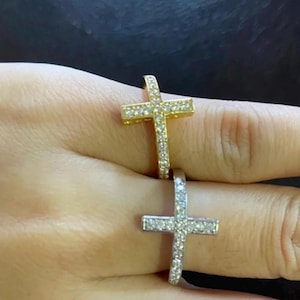May include: Two gold and silver rings with a cross design. The cross is encrusted with small clear stones.
