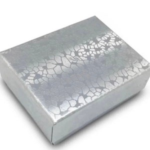 May include: A silver jewelry box with a textured, patterned design.
