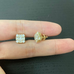 May include: A pair of gold square-shaped earrings with small clear cubic zirconia stones.