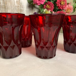 May include: Set of four red glass tumblers with a diamond pattern. The glasses are clear and have a vintage look.