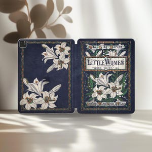 Könnte beinhalten: Eine offene Tablet-Hülle mit marineblauem Hintergrund und weißen Lilien-Illustrationen. Die Hülle zeigt den Titel "Little Women" mit Text aus "The Lily Series" und dem Verlag "London, Ward, Lock & Tyler."