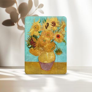 May include: A tablet case featuring a print of Vincent van Gogh's "Sunflowers" painting. The case displays a vibrant bouquet of yellow sunflowers in a yellow vase against a blue and yellow background. The case is rectangular with rounded corners.