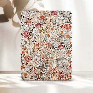 Può includere: Una custodia rettangolare per tablet caratterizzata da un fitto e complesso motivo botanico con fiori stilizzati e foglie intrecciate nei toni del terracotta, rosso scuro, blu tenue e crema, con linee di piegatura verticali visibili.