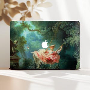 May include: Laptop skin with a classical painting of a woman on a swing in a verdant forest. The artwork uses shades of green, pink, and white, with an Apple logo in the centre. The design evokes elegance and historical art, suitable for a laptop.