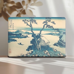 Puede incluir: Funda para portátil con un estampado de paisaje japonés. El diseño presenta una escena serena con un pequeño barco, una cabaña y montañas en tonos azules y beige. La obra de arte recuerda a las estampas japonesas tradicionales.