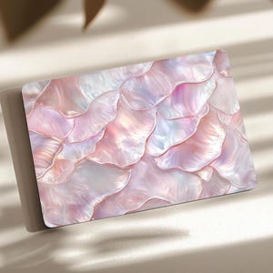 Puede incluir: Una pegatina rectangular para portátil con un patrón repetitivo de escamas superpuestas iridiscentes en tonos rosa y blanco. La superficie presenta un acabado nacarado suave con reflejos de luz tenues y gradientes sutiles de colores pastel.