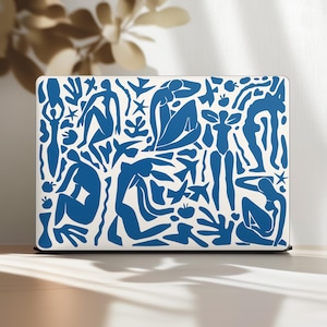 Puede incluir: Una funda blanca para portátil con un diseño azul al estilo Matisse. El diseño incluye figuras humanas abstractas, hojas y otras formas. La funda es rectangular y se apoya sobre una superficie clara.
