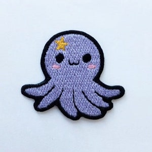 May include: A purple embroidered octopus with a yellow star on its head and pink cheeks. The octopus has eight tentacles and a cute, cartoon-like face.