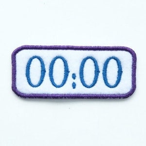 Puede incluir: Parche rectangular blanco con borde morado y texto bordado en azul que dice "00:00".