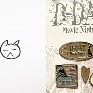 Puede incluir: Cuatro pines de plata con diferentes diseños. Un pin es de forma ovalada con el texto "D-DAY Movie Night". Otro pin es de forma cuadrada con el texto "Agust D". El tercer pin es en forma de corazón y el cuarto pin es un gato de dibujos animados con una expresión de sorpresa.