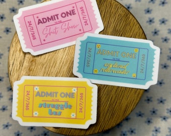 May include: Three colorful ticket-shaped stickers with the text "Admit One" and different humorous phrases. The stickers are pink, blue, and yellow with white text and black outlines.