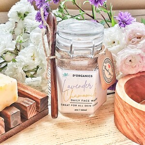 Op de afbeelding: Een glazen pot met een bruine houten lepel, gevuld met een lichtbruine gezichtsreiniger. De pot heeft een etiket met de tekst "Lavender Chamomile Daily Face Wash Great for All Skin Types 4oz | 120ml" en een klein bruin kaartje met de tekst "Thank you".