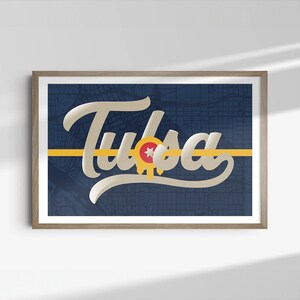 May include: A framed print with a navy blue background featuring a stylized white and gold inscription of "Tulsa" with a yellow stripe and the city seal in the center.