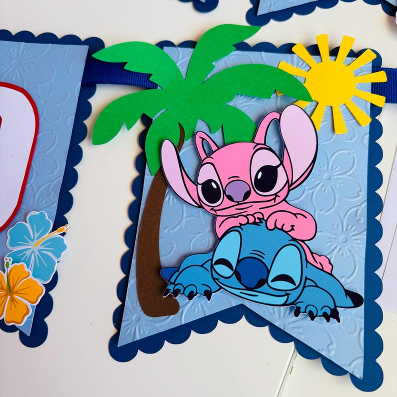 Puede incluir: Una pancarta azul con borde festoneado presenta un tema tropical. Incluye una palmera, un sol amarillo y los personajes de dibujos animados Stitch y Angel. La pancarta tiene un fondo texturizado con motivos florales.