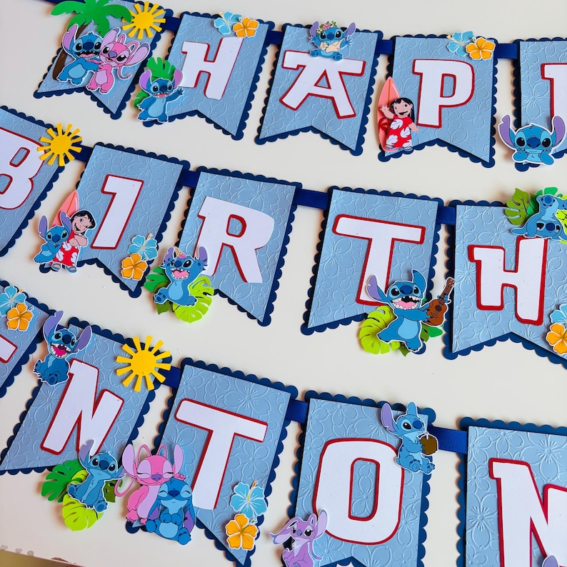 Puede incluir: Una pancarta azul con las palabras "HAPPY BIRTHDAY" en letras blancas. Decorada con im&aacute;genes de Stitch y flores tropicales. Ideal para una fiesta de cumplea&ntilde;os.