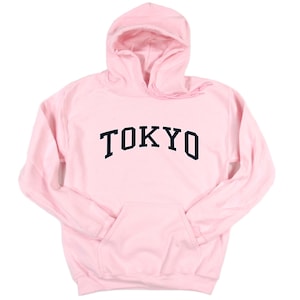 May include: A pink hooded sweatshirt with the word "TOKYO" printed in black on the front.