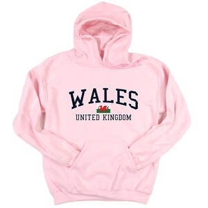 Puede incluir: Sudadera con capucha rosa con el texto "WALES UNITED KINGDOM" y la bandera de Gales.