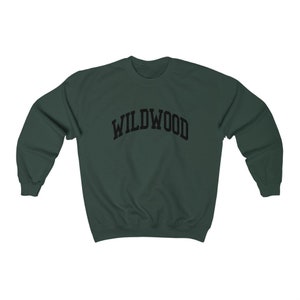 May include: A dark green sweatshirt with the word "WILDWOOD" arched across the chest in black block letters. The sweatshirt has a crew neck and long sleeves. The garment is made of a soft, comfortable material.