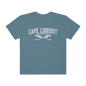 K&ouml;nnte beinhalten: Ein blaues T-Shirt mit einer wei&szlig;en Grafik, auf der "CAPE LOOKOUT NORTH CAROLINA" mit zwei gekreuzten Rudern steht.