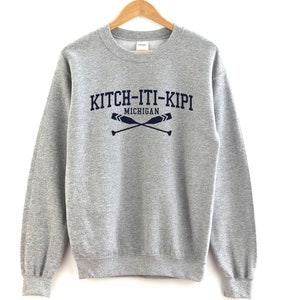 May include: A gray sweatshirt with a navy blue print that says "KITCH-ITI-KIPI MICHIGAN" with two crossed oars.