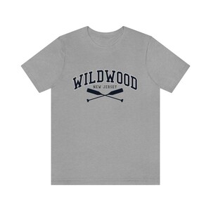 May include: A heather grey t-shirt with a navy blue graphic of the text "WILDWOOD NEW JERSEY" with two crossed oars.