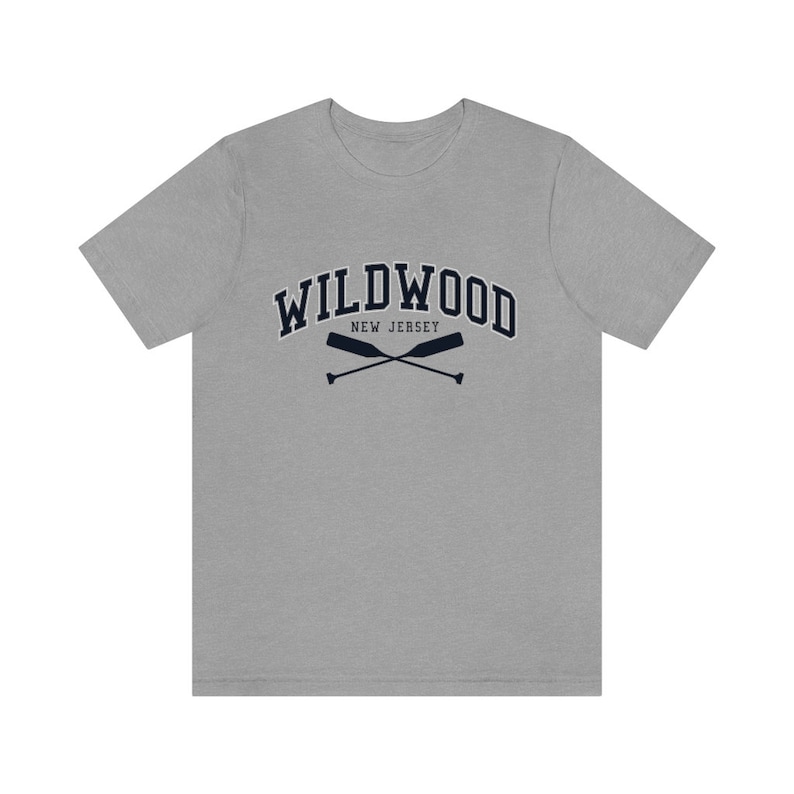 May include: A heather grey t-shirt with a navy blue graphic of the text "WILDWOOD NEW JERSEY" with two crossed oars.