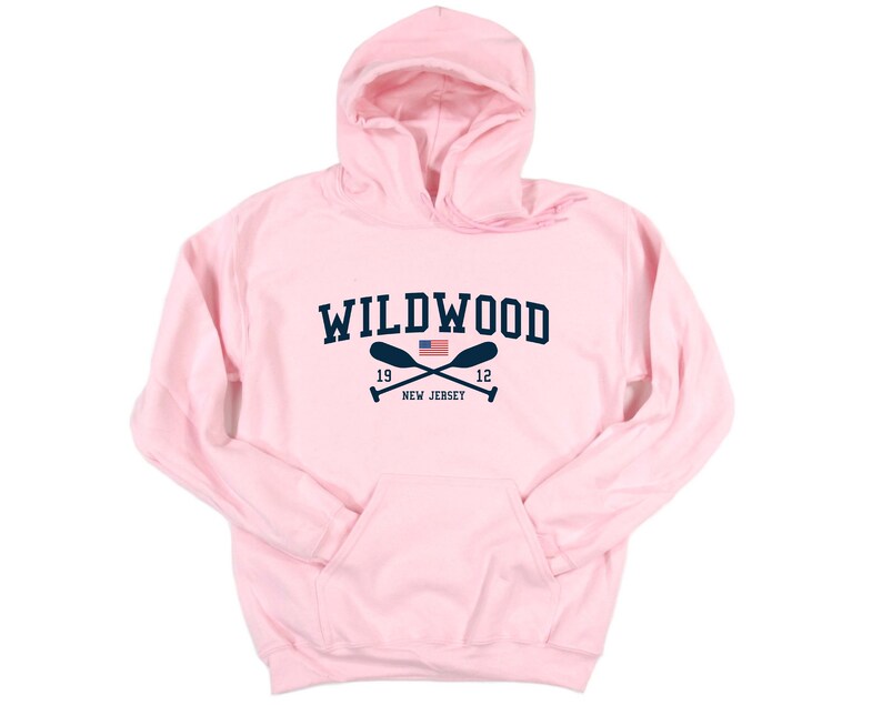 Pu&ograve; includere: Felpa con cappuccio rosa con una grafica blu navy del testo "WILDWOOD" con remi incrociati e una piccola bandiera americana. Il testo "19 12 NEW JERSEY" &egrave; sotto la grafica.