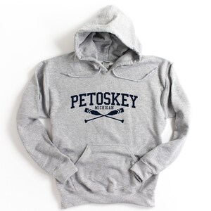 May include: A gray hooded sweatshirt with the text "Petoskey Michigan" and two crossed oars in navy blue.