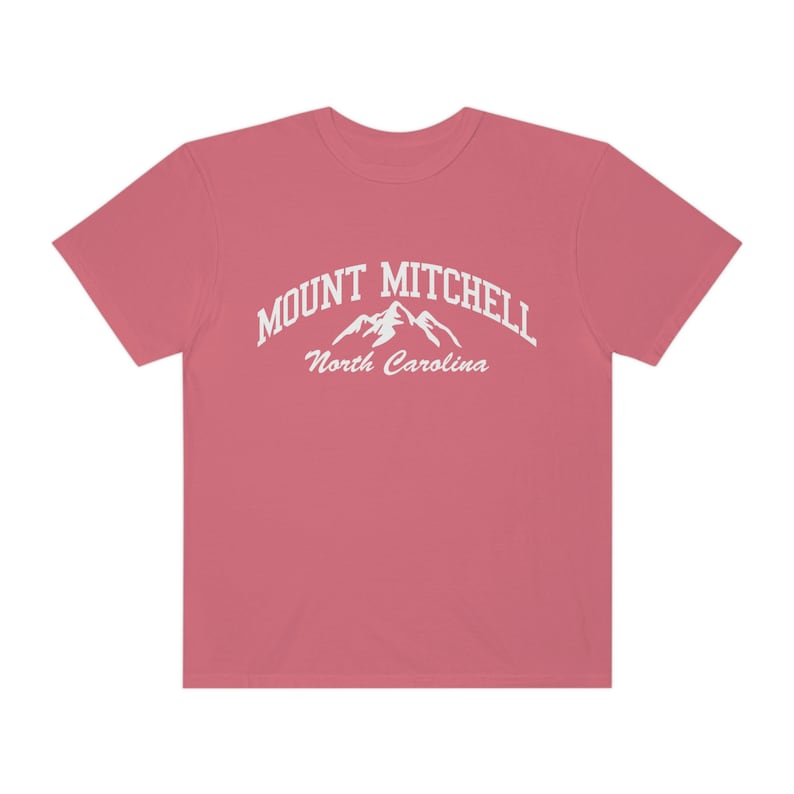 May include: A pink t-shirt with a white graphic of a mountain range and the text "MOUNT MITCHELL North Carolina".