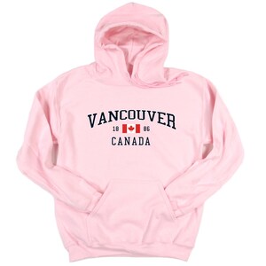 May include: Pink hooded sweatshirt with the text "VANCOUVER 18 86 CANADA" and a Canadian flag graphic.