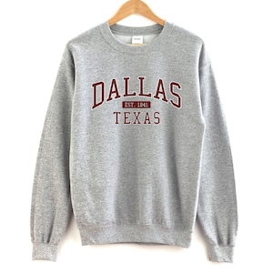 May include: A gray sweatshirt with a maroon print that says "Dallas Est. 1941 Texas"