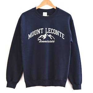 May include: Navy blue sweatshirt with a white graphic of mountains and the text "MOUNT LECONTETennessee".