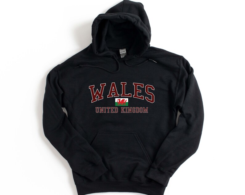 Puede incluir: Sudadera con capucha negra con el texto "WALES UNITED KINGDOM" en letras granate y un gr&aacute;fico de la bandera del drag&oacute;n rojo.