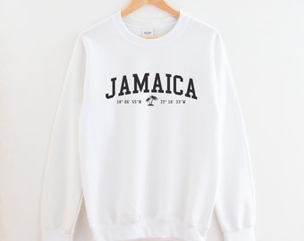 May include: White sweatshirt with black text that reads "Jamaica" and coordinates "18° 06' 55" N 77° 16' 33" W" with a palm tree graphic.
